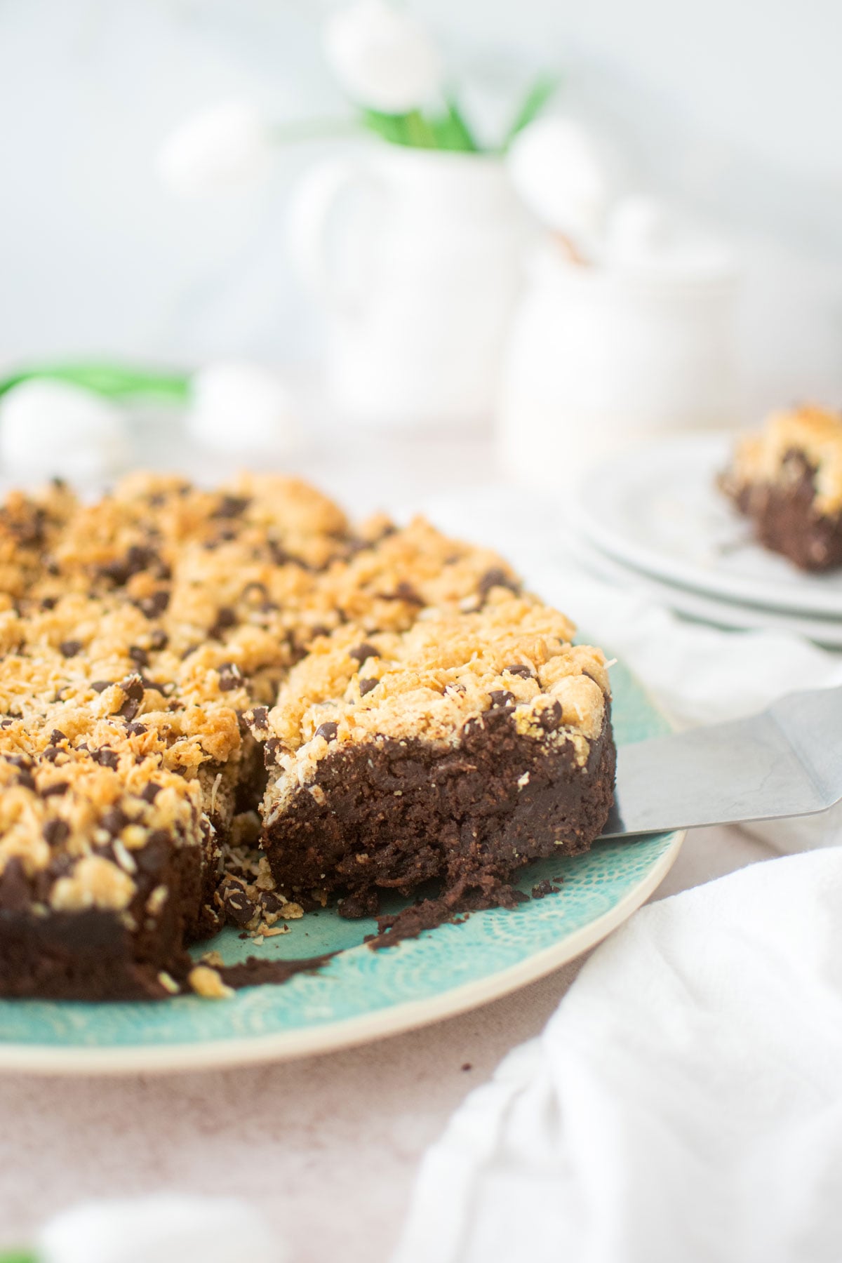 eggless chocolate carrot cake on a green cake plate cut into square slices.
