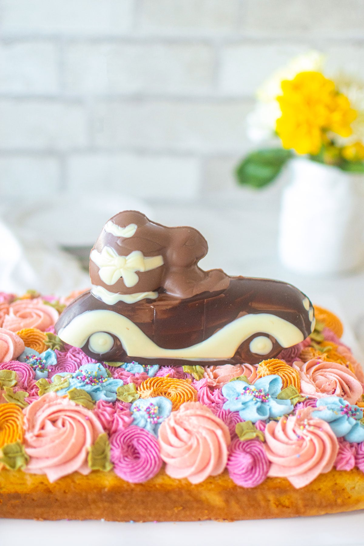 pastel flower sheet cake with a chocolate bunny driving a convertible on top.