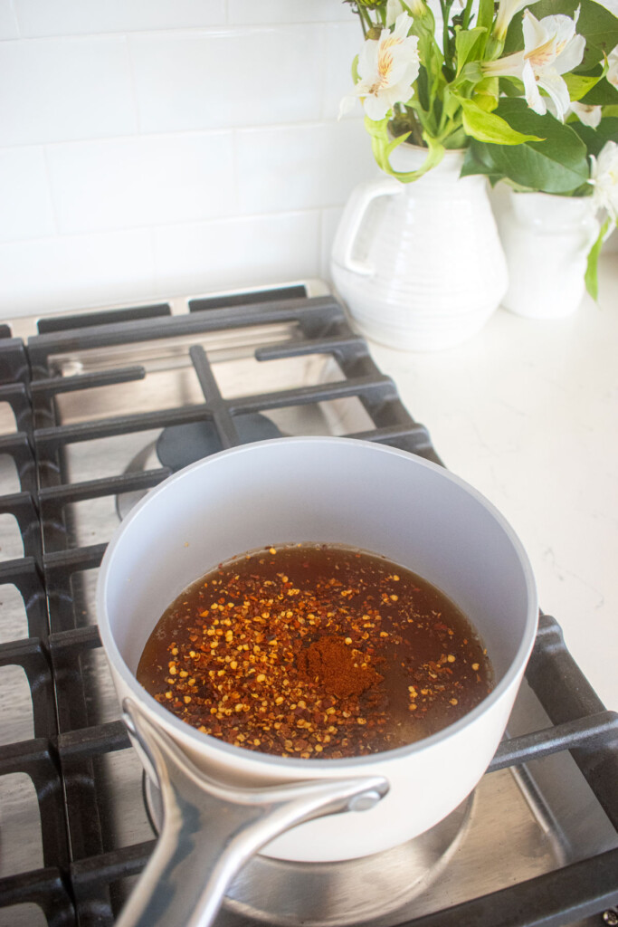 homemade organic hot honey being cooked in a small pot over the stovetop.
