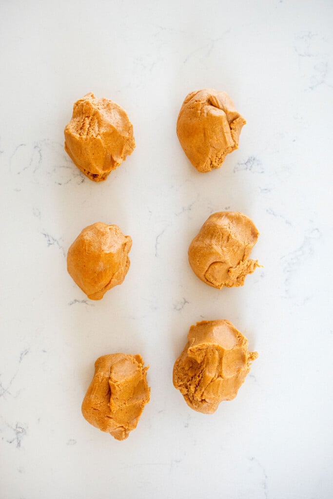 mini peanut butter oat dog treat dough in 6 balls on the countertop.