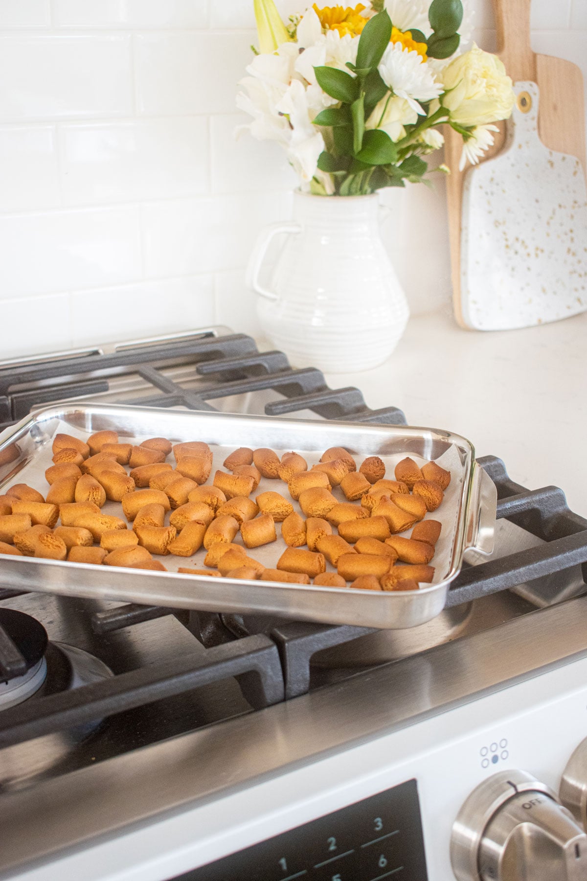 mini peanut butter oat dog treats on a sheet pan on the stove.
