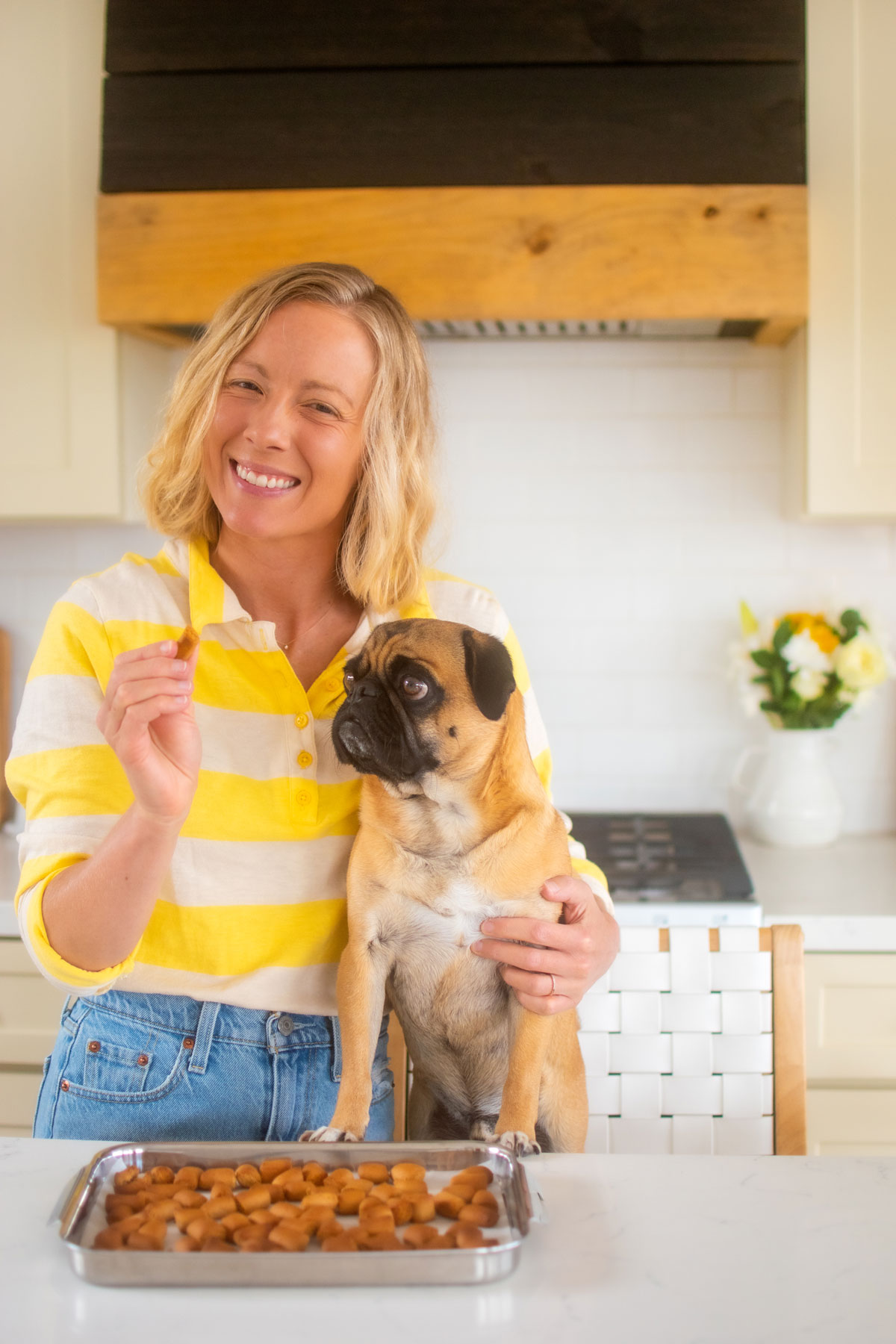 woman and pug in kitchen eating mini peanut butter dog treats.