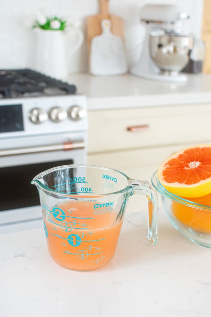 freshly squeezed pink grapefruit juice in a pyrex measuring cup on the kitchen counter.