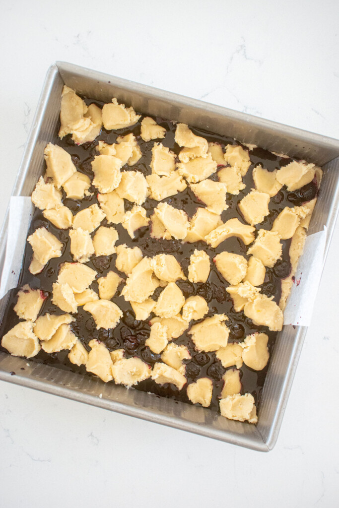 sourdough blueberry crumb bars in a square baking pan ready to be baked sitting on a white marble counter.