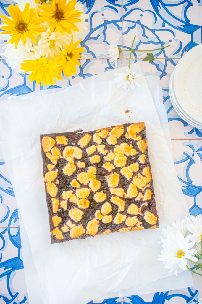 sourdough blueberry crumb bars on white parchment paper on a blue tile table.