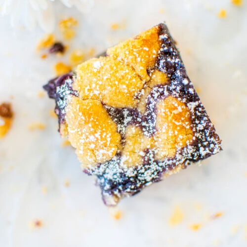 one sourdough blueberry crumb bar on a white piece of parchment paper.