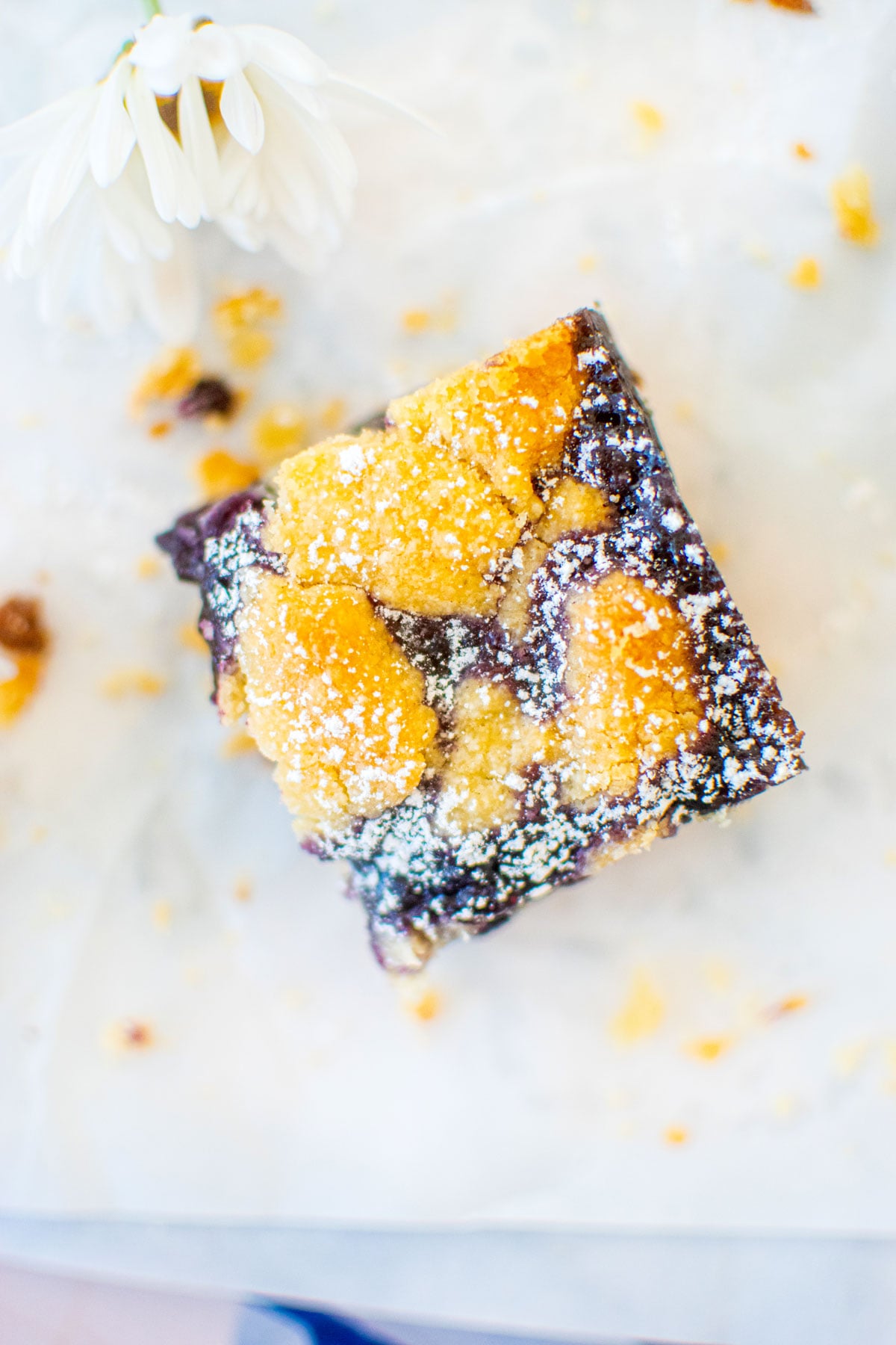 one sourdough blueberry crumb bar on a white piece of parchment paper.