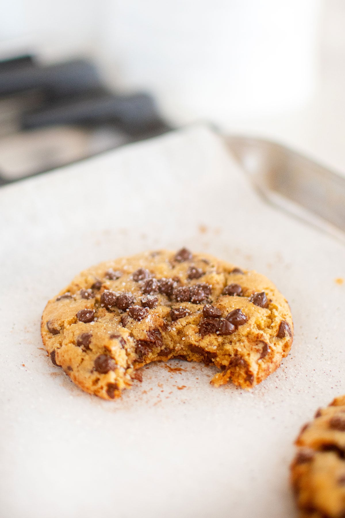 vanilla sea salt chocolate chip cookie on a baking sheet with a bite taken out.