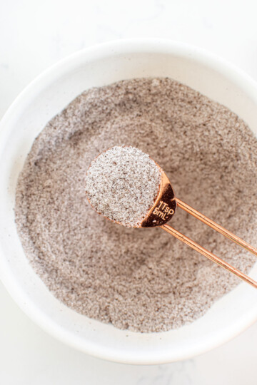 vanilla sea salt in a bowl with a copper teaspoon on a white marble counter.