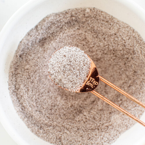 vanilla sea salt in a bowl with a copper teaspoon on a white marble counter.