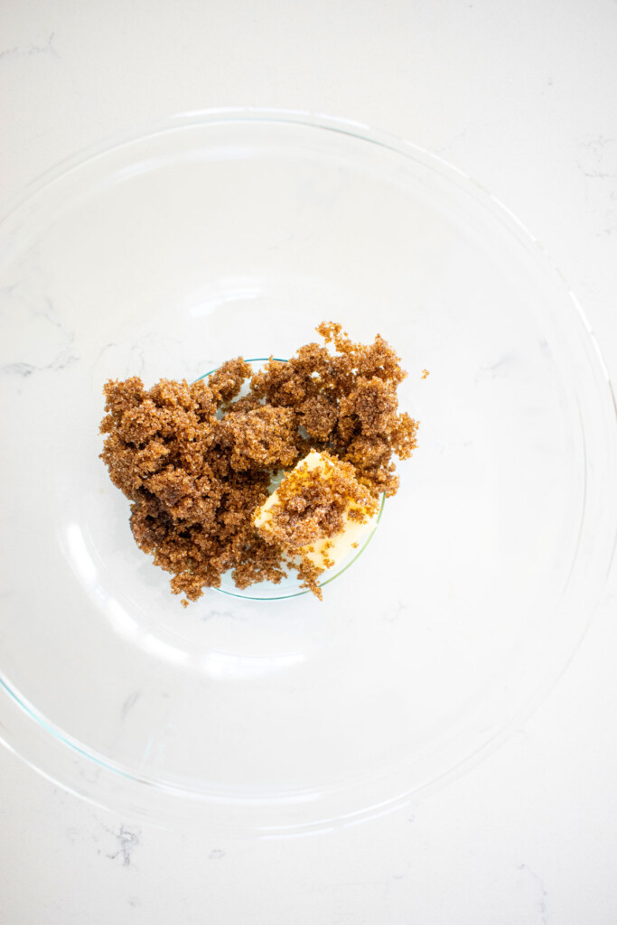brown sugar and butter in a glass mixing bowl on a white marble counter.