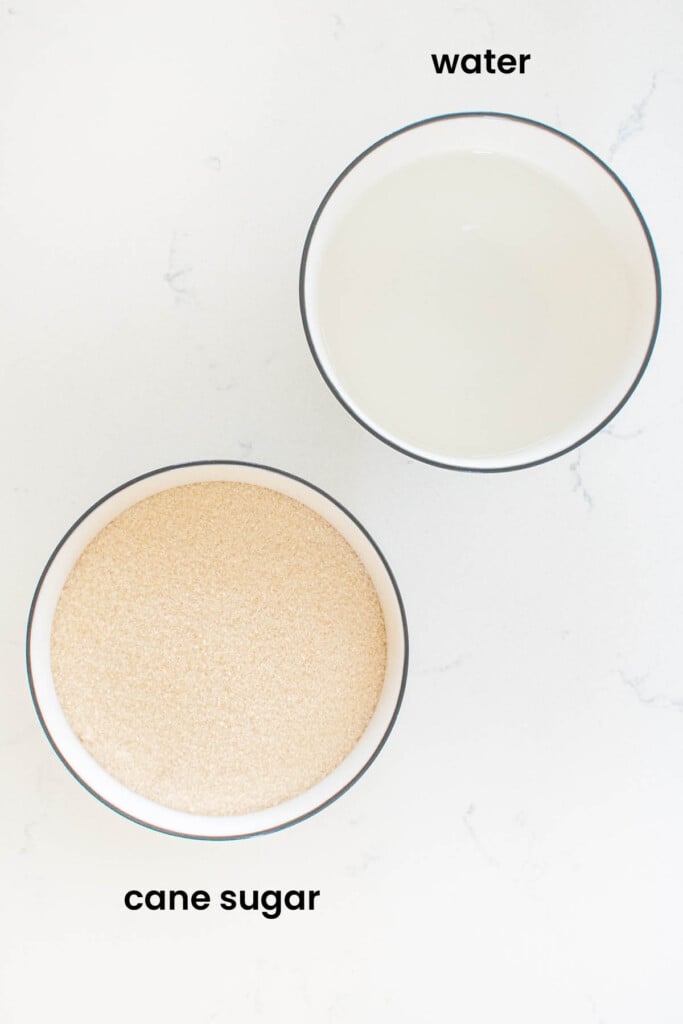 a bowl of cane sugar and a bowl of water in a bowl on a white countertop.