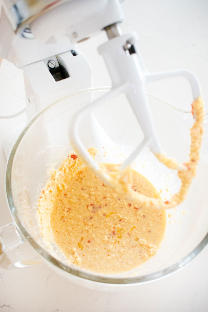 wet ingredients mixed in a glass mixing bowl for strawberry snack cake on a marble counter.