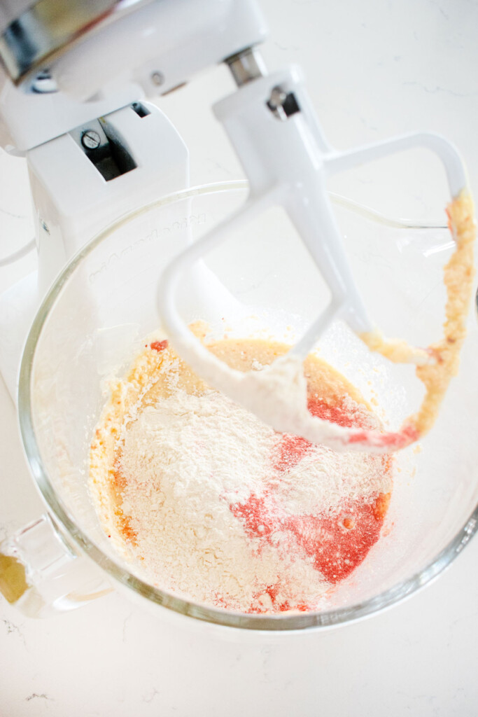 ingredients for strawberry cake batter in a glass mixing bowl on a white marble counter.