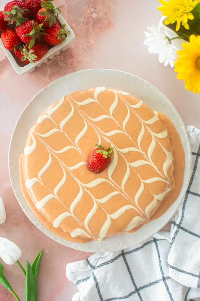 strawberry snack cake with pink ganache and white chevron design with a strawberry on top on a white plate.