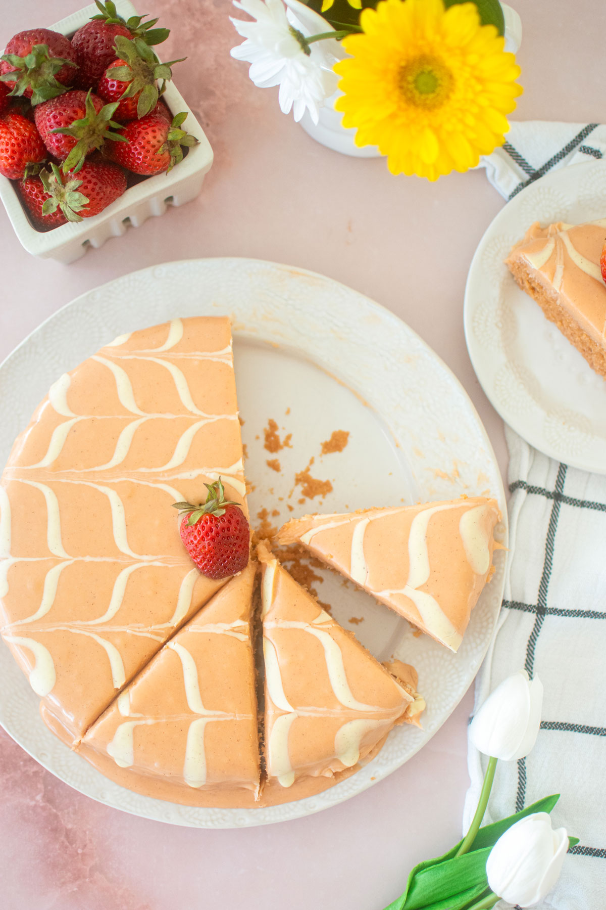 sliced strawberry snack cake with pink ganache and white chevron design with a strawberry on top on a white plate.