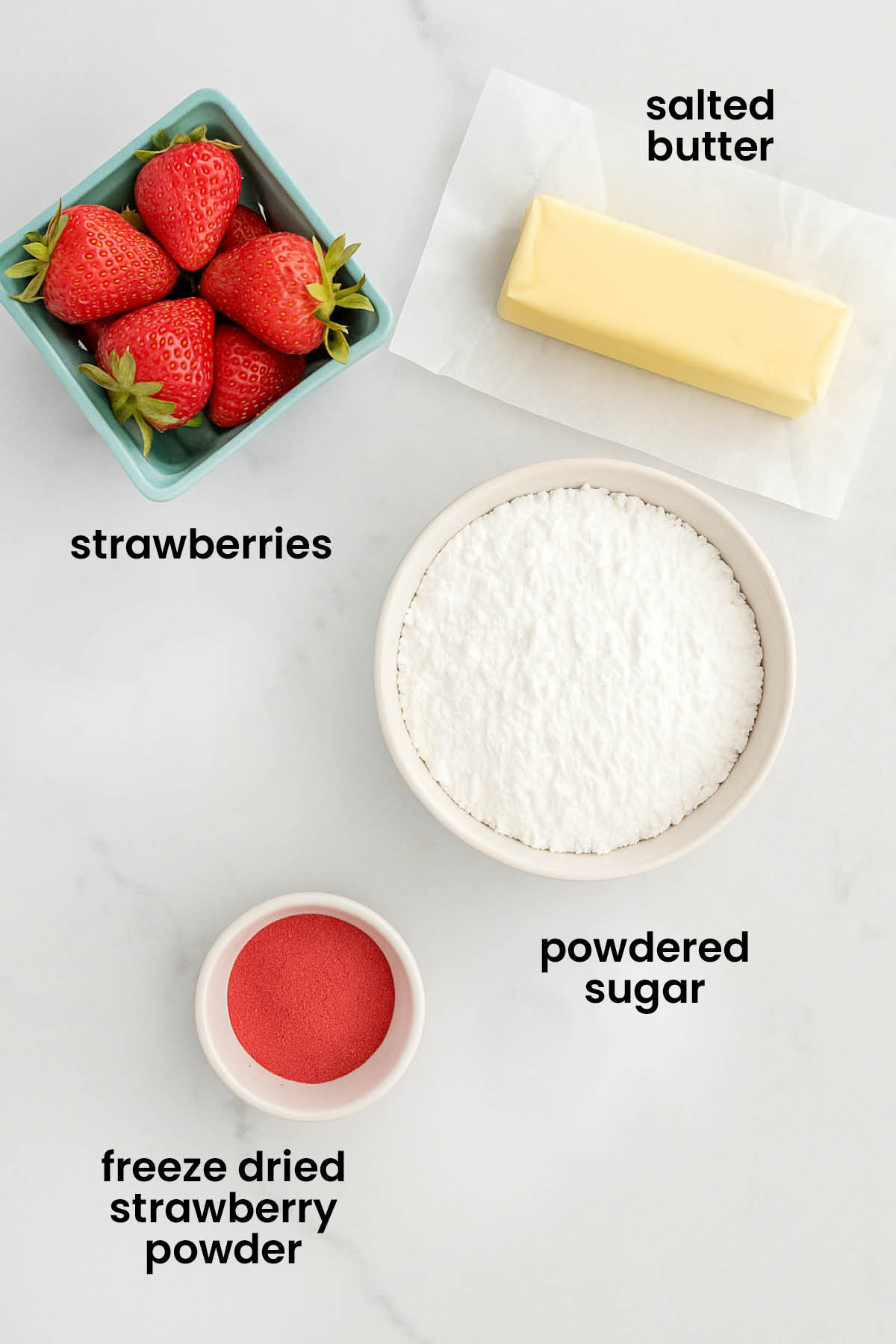 individual ingredients for strawberry buttercream with fresh or freeze dried strawberries laid out against a white background.