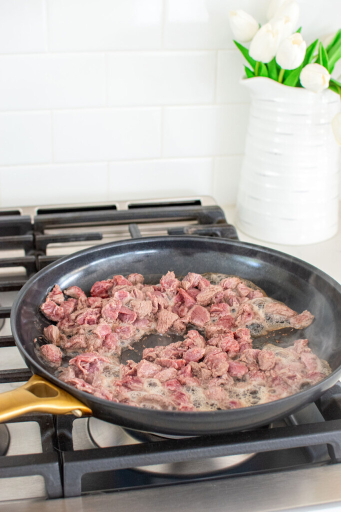 organic stew meat cooking in a large skillet on the stovetop.