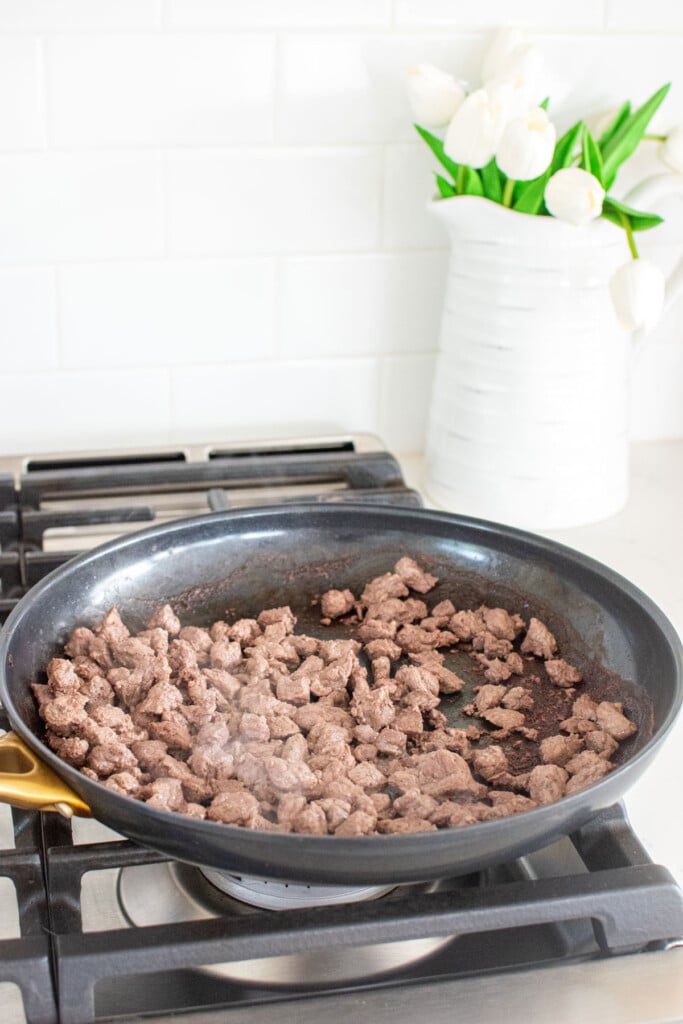 organic stew meat cooking in a large skillet on the stovetop.