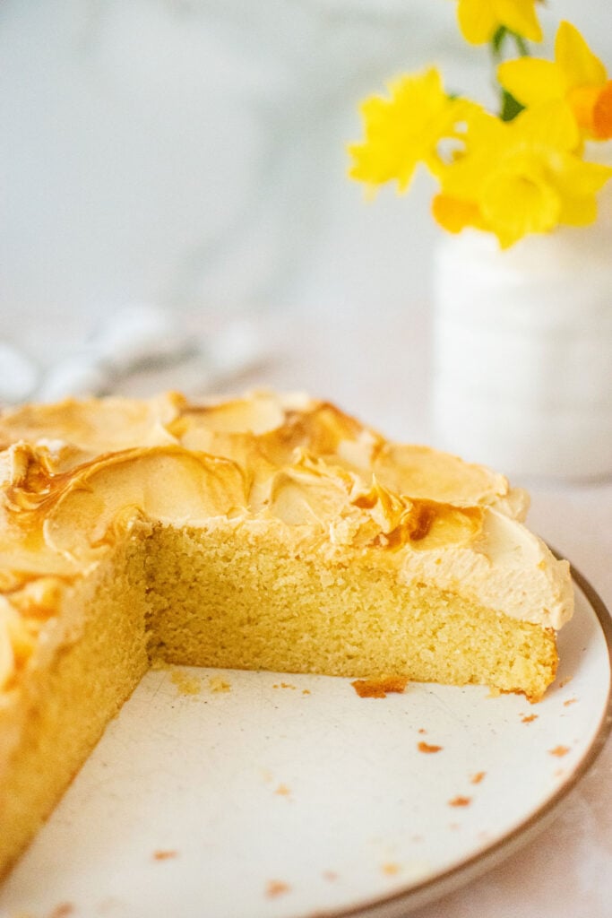 caramel buttercream frosting on vanilla cake cut exposing the cake on a plate.