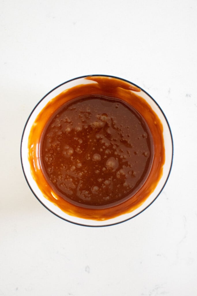 caramel in a bowl that has been microwaved so it's melted on a white countertop.