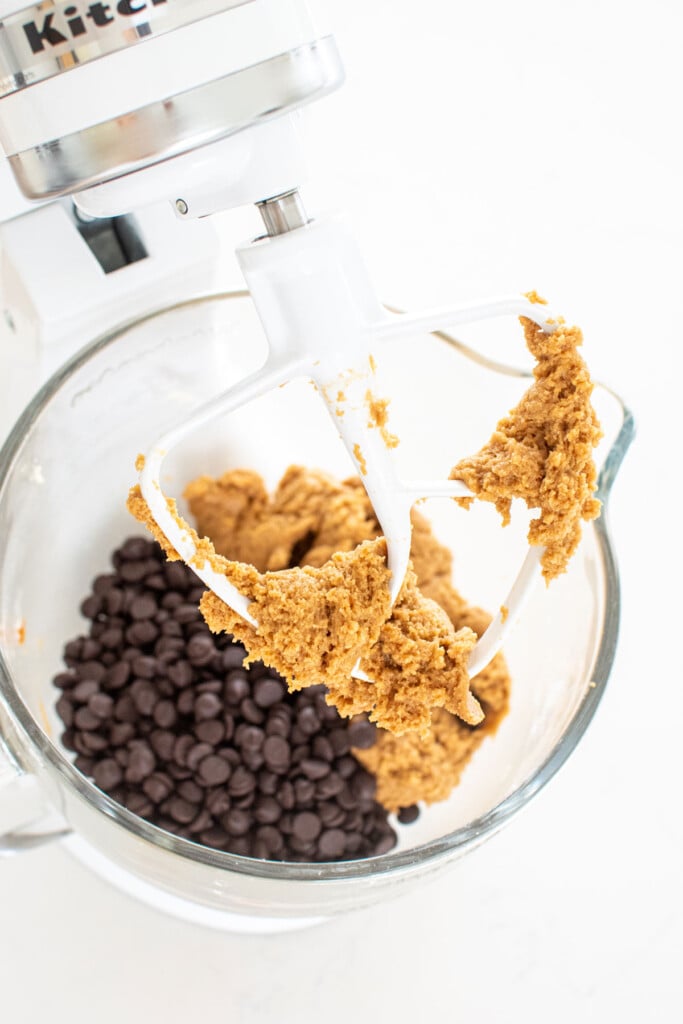 caramel cookie dough with chocolate chips in a galss mixing bowl on a white countertop.