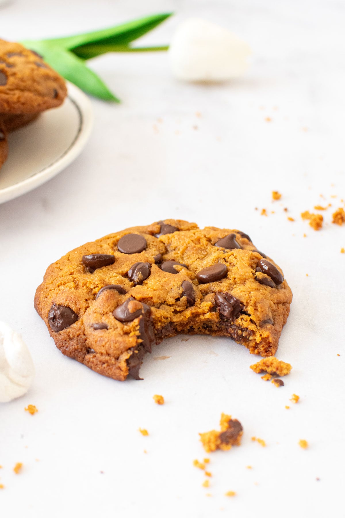 caramel chocolate chip cookie with homemade caramel with a bite taken out on a white marble countertop.
