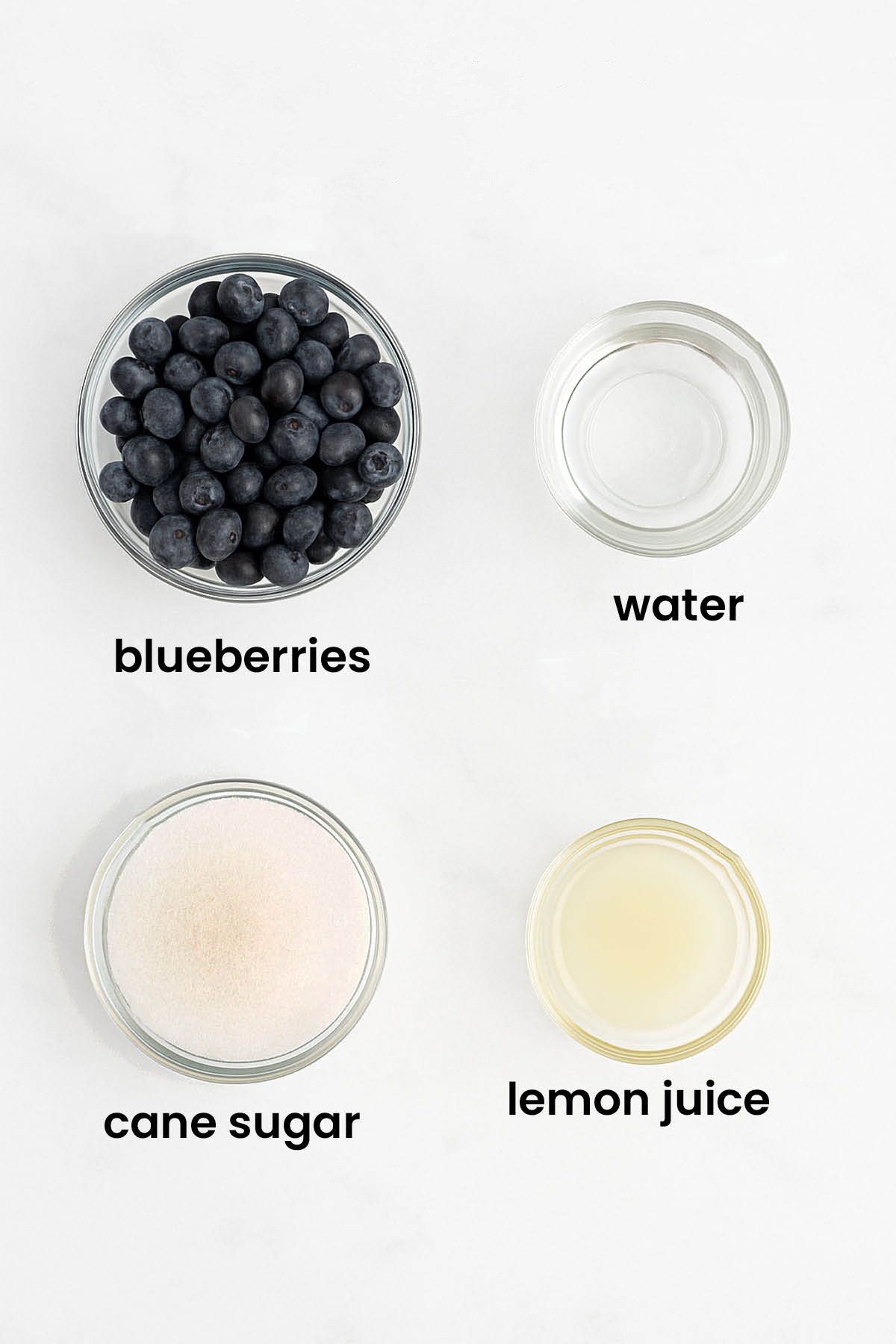 individual ingredients for homemade blueberry syrup laid out against a white background.