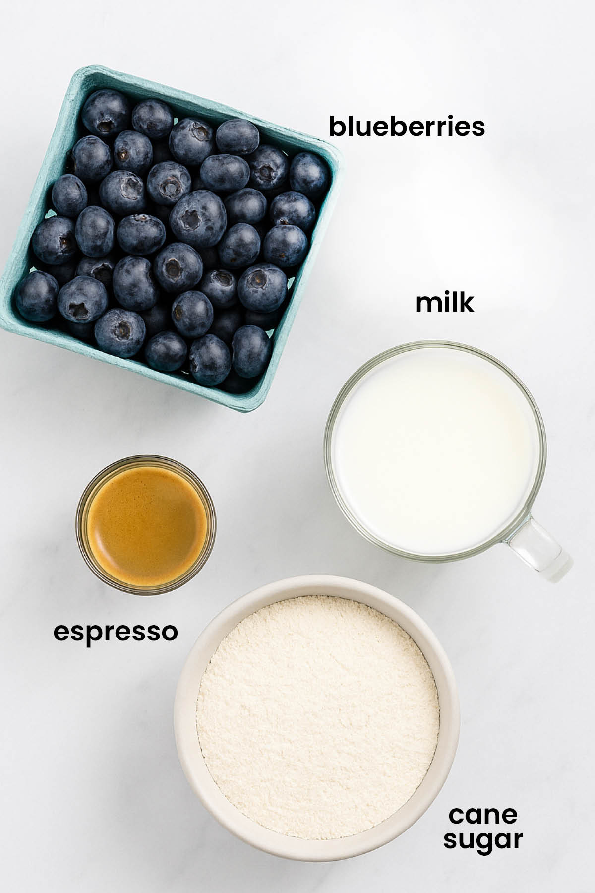 individual ingredients for iced blueberry latte laid out against a white background.