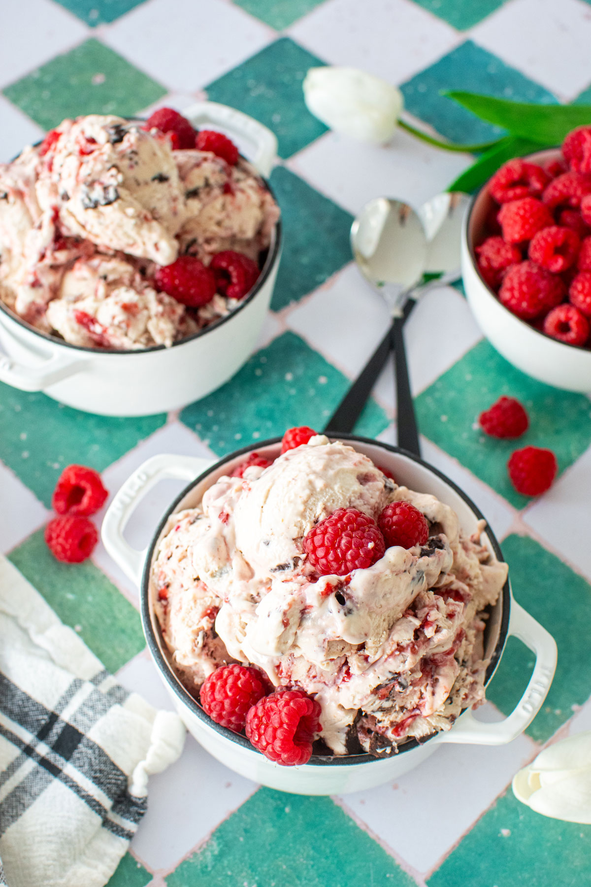 raspberry chocolate chip ice cream on a green tile table with with fresh raspberries.