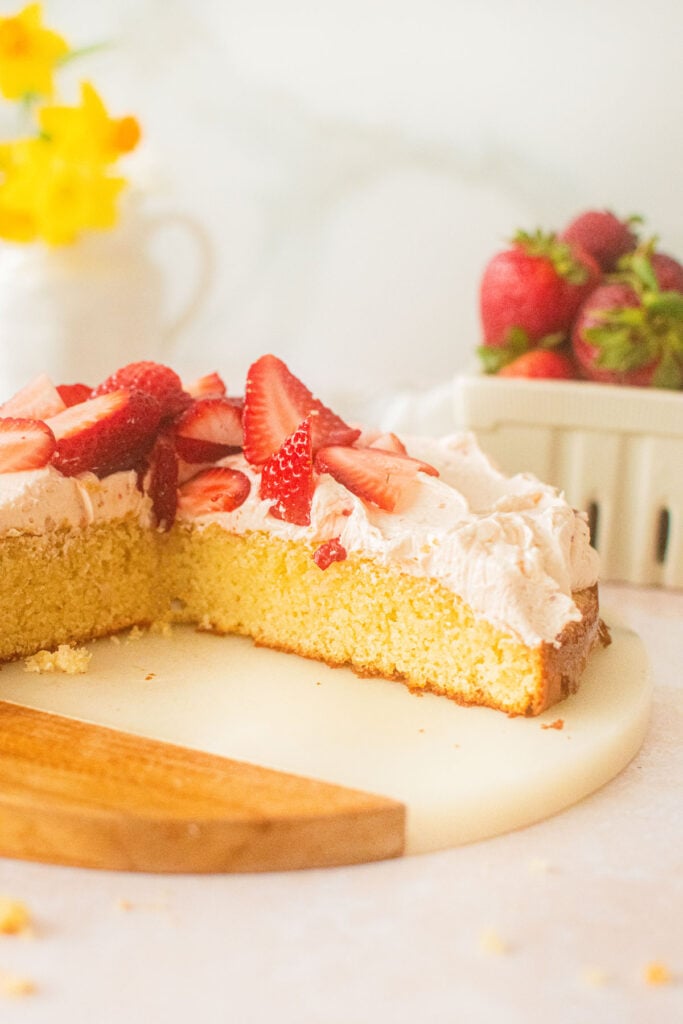 strawberry buttercream frosting on vanilla cake with the cake cut into.