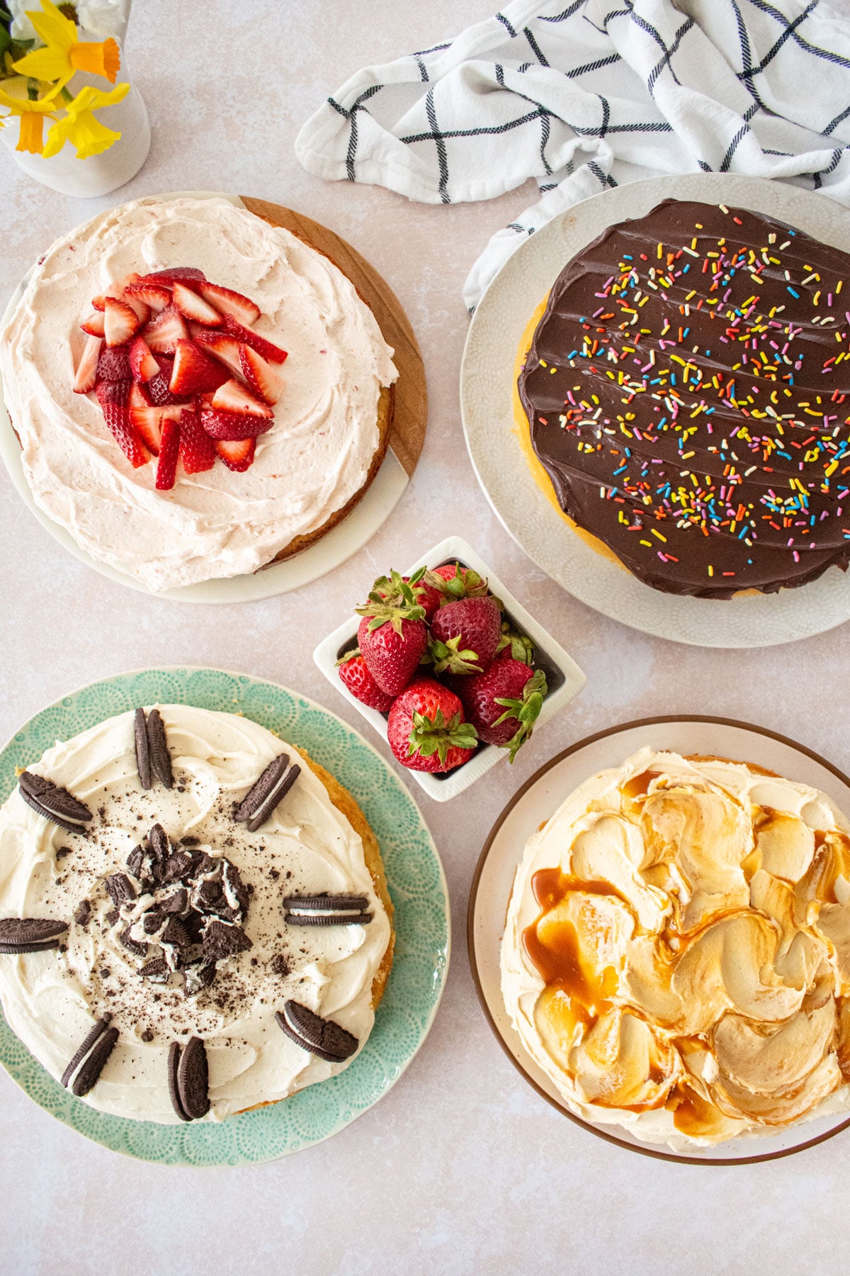 vanilla cake frosted 4 different ways, one with strawberry buttercream, one with chocolate ganache, one with cream cheese, one with caramel.
