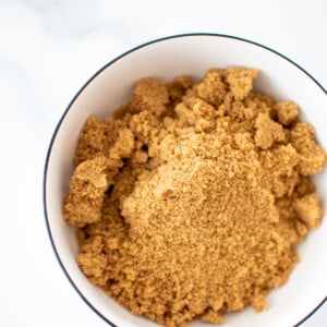 organic light brown sugar in a bowl on a white marble counter.