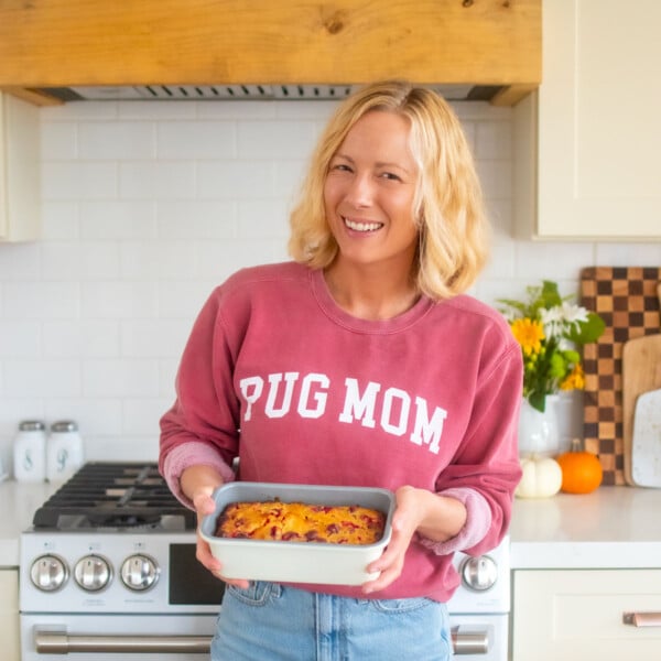 woman in kitchen wearing a red sweatshirt with pug mom in text on it.