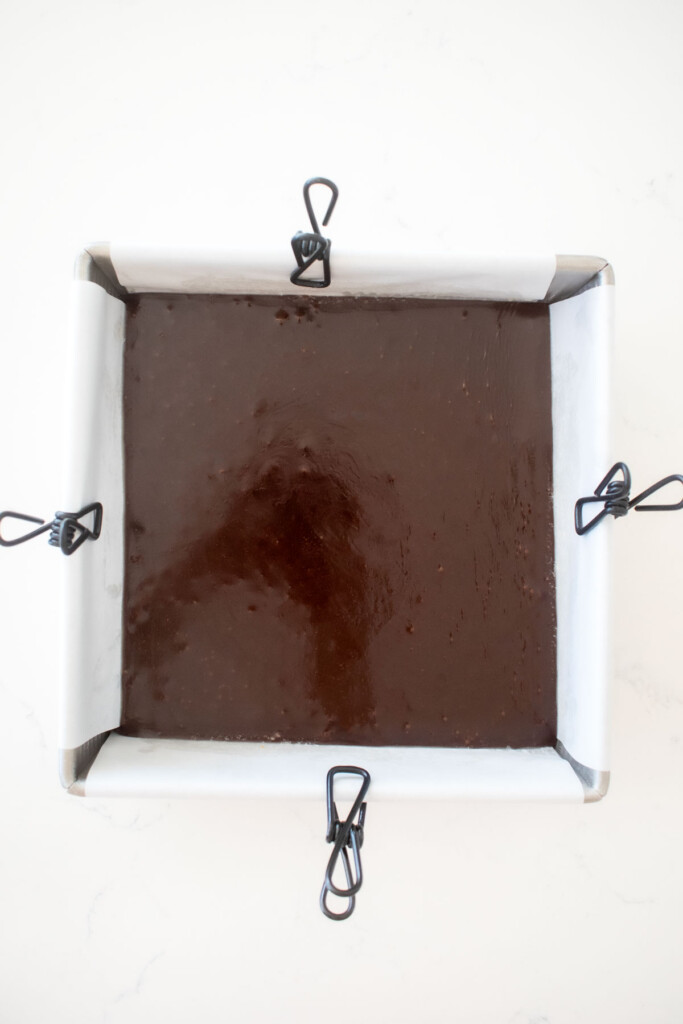 homemade chewy chocolate caramel candy in a baking pan on a white marble counter.