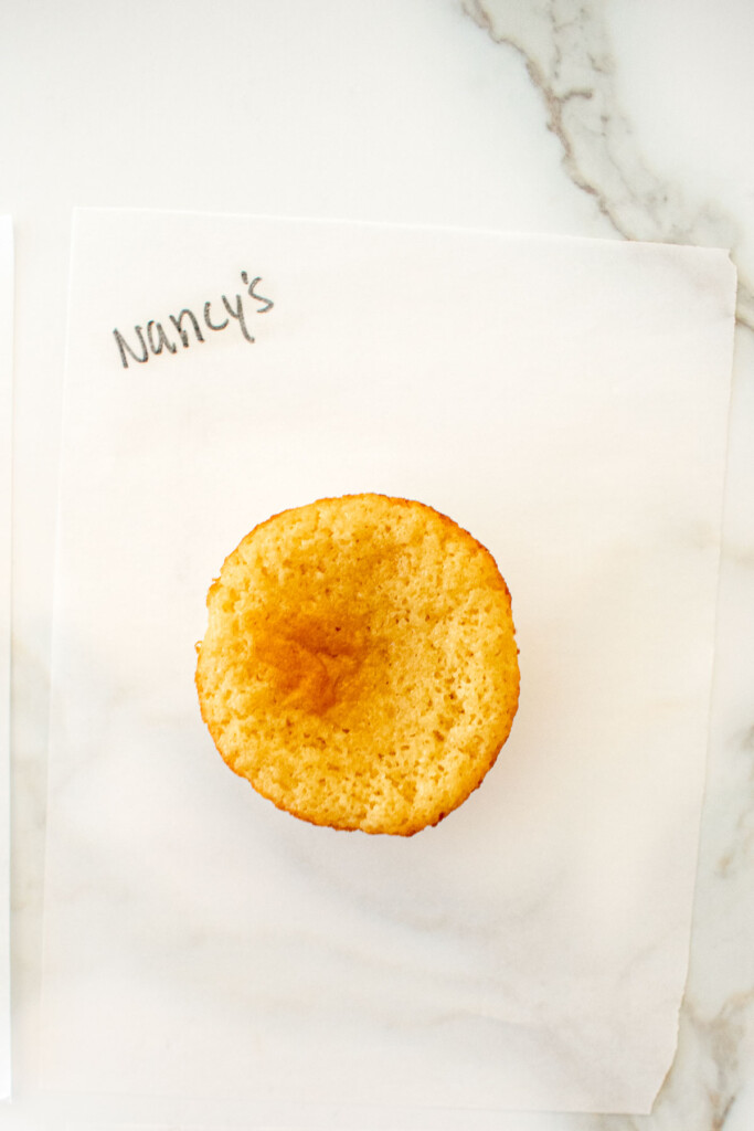 vanilla cupcake on a white piece of parchment paper on a marble counter with the butter name used written in black marker.