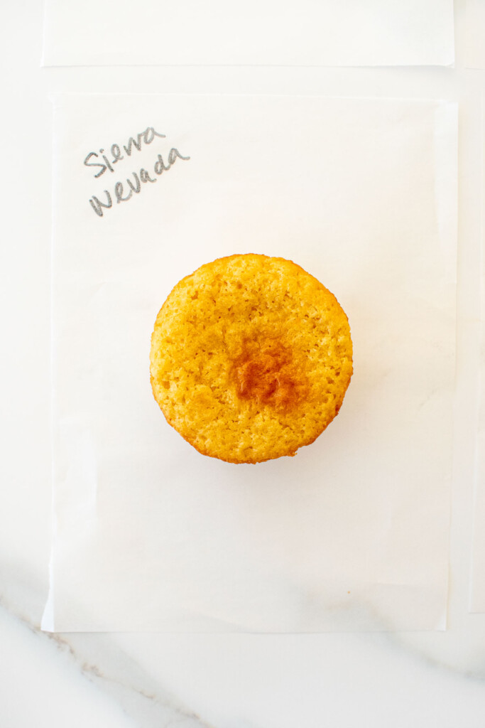 vanilla cupcake on a white piece of parchment paper on a marble counter with the butter name used written in black marker.