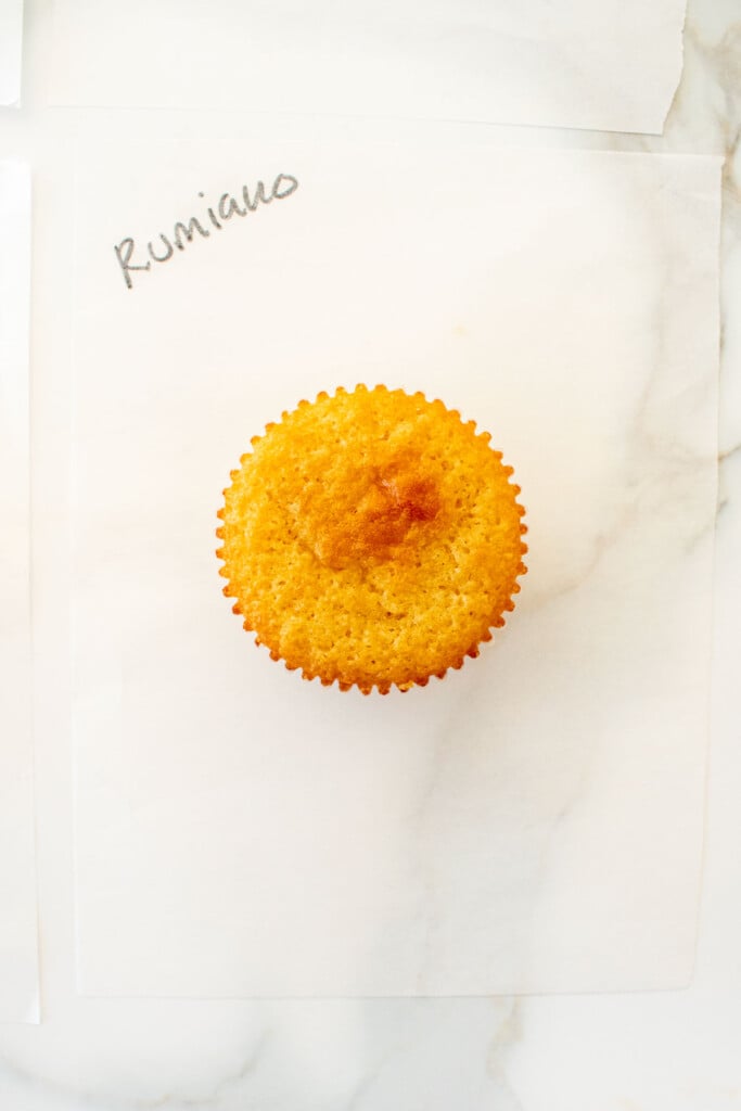 vanilla cupcake on a white piece of parchment paper on a marble counter with the butter name used written in black marker.