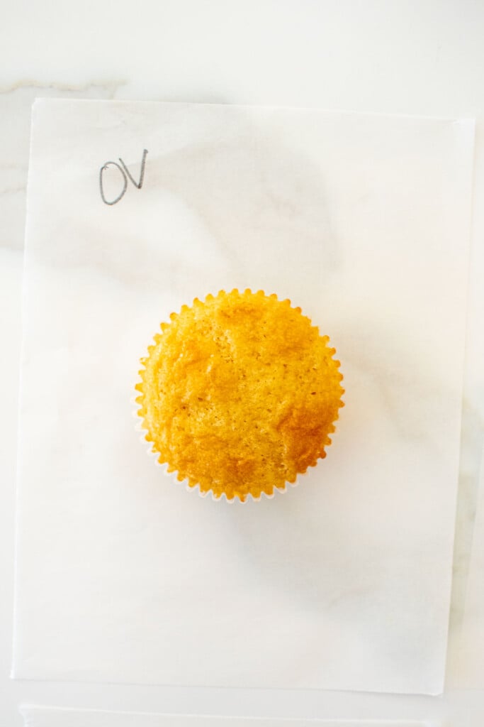 vanilla cupcake on a piece of parchment paper on a white marble counter made with organic valley butter.