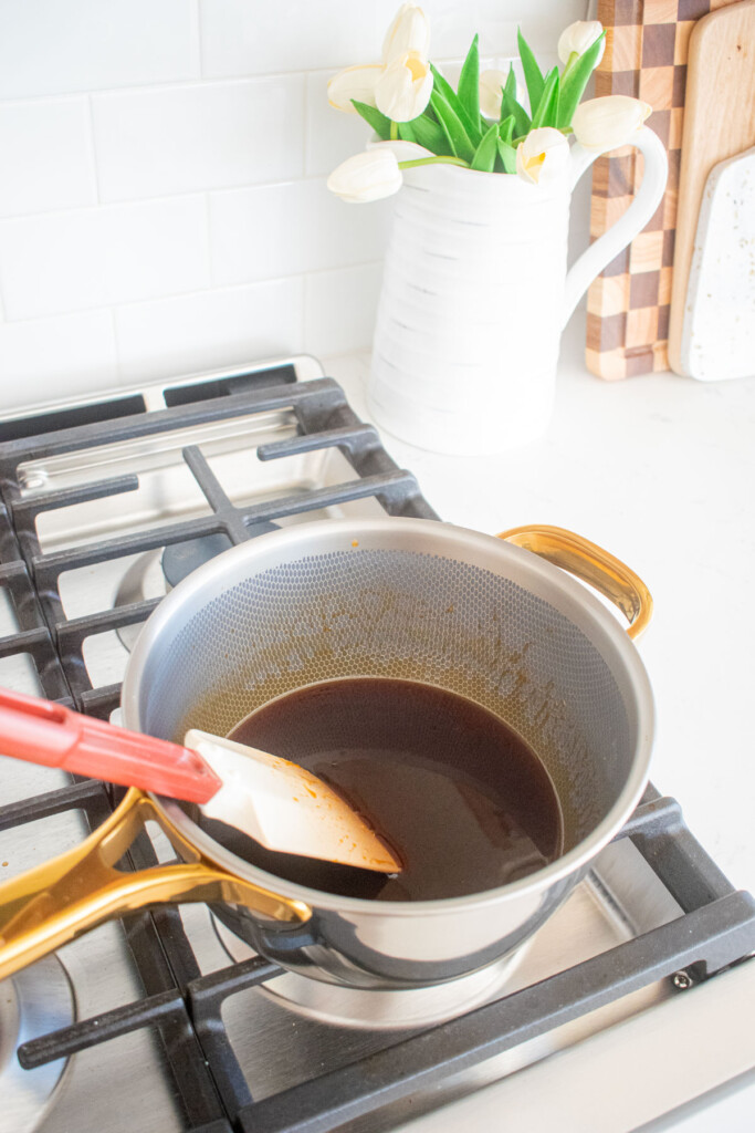 homemade caramel sauce with bone broth being cooked on the stovetop in a titanium pot.
