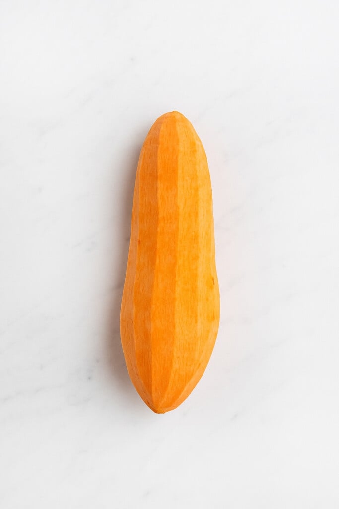 peeled sweet potato on a white marble counter.