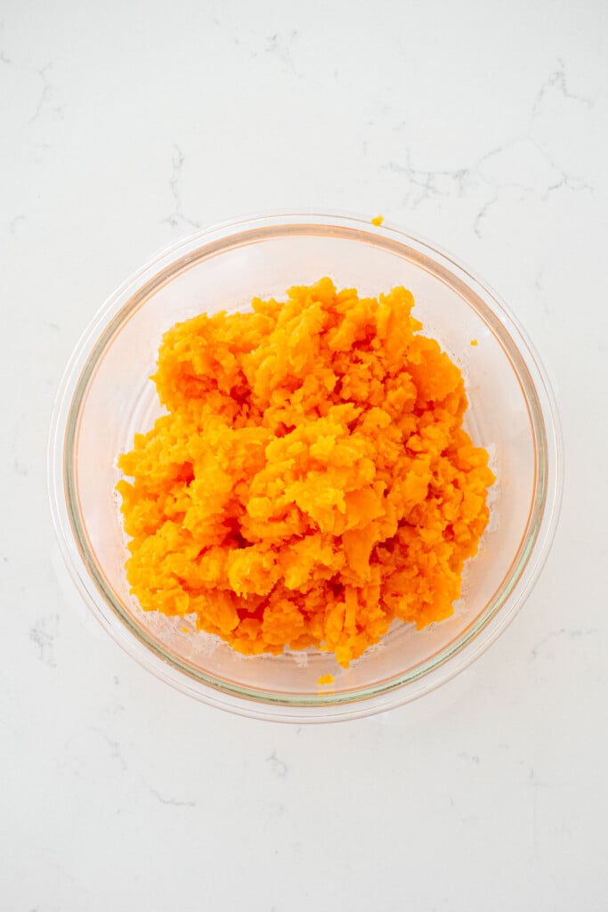 mashed sweet potato in a glass tupperware on a white marble counter.