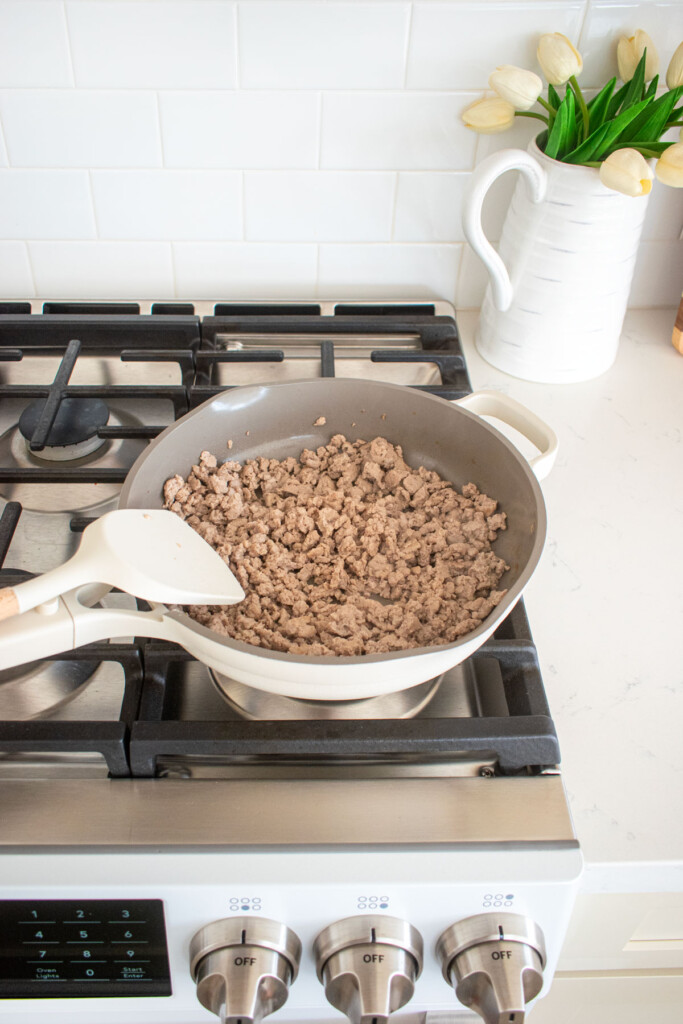 large skillet on the stovetop with ground turkey being cooked.