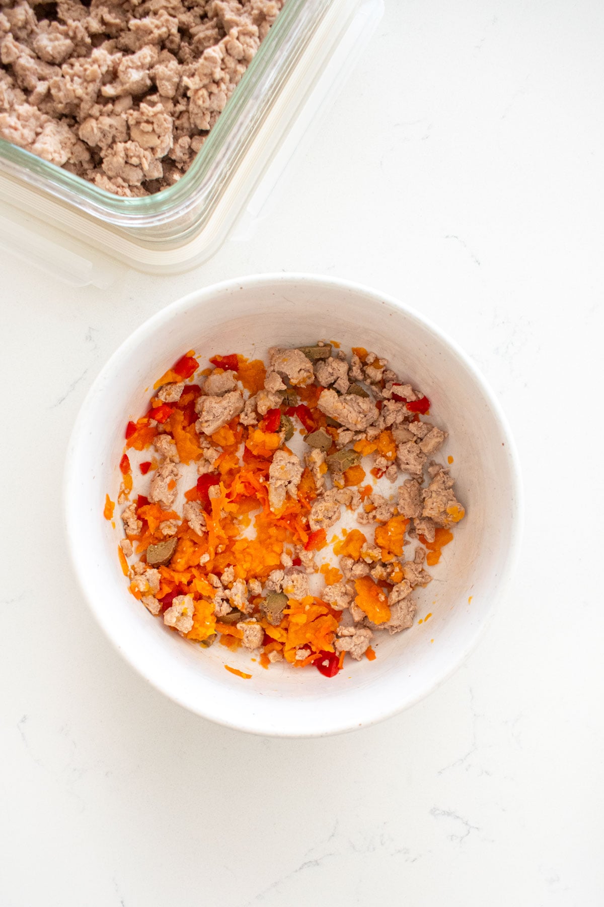 homemade ground turkey dog food in a bowl on a white marble counter.