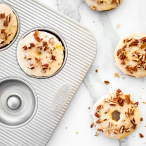 usa pan donut pan with maple pecan donuts on a white marble counter.