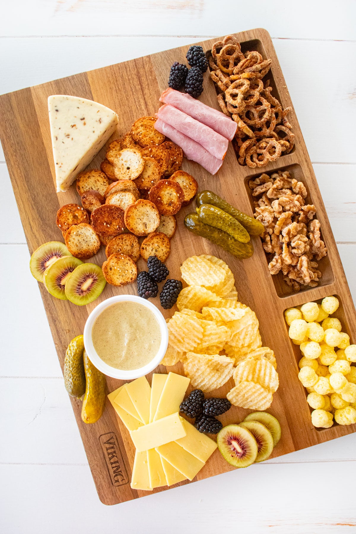 wood serving board with charcuterie on a white wood table.