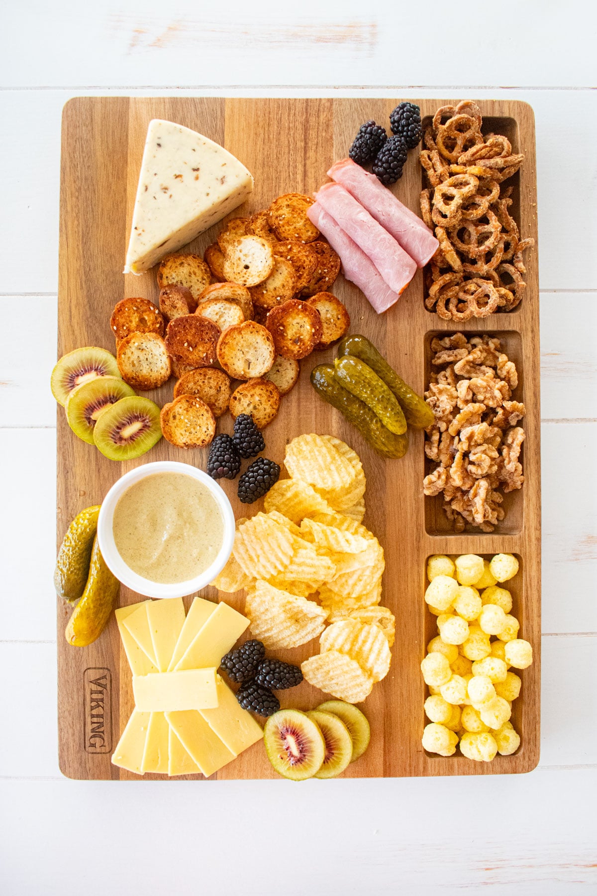 wood serving board with charcuterie on a white wood table.