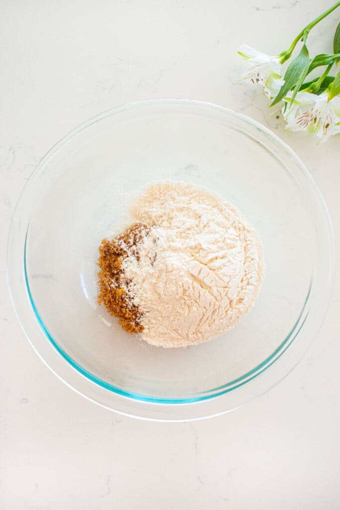 ingredients for streusel topping in a glass mixing bowl on a white marble counter.