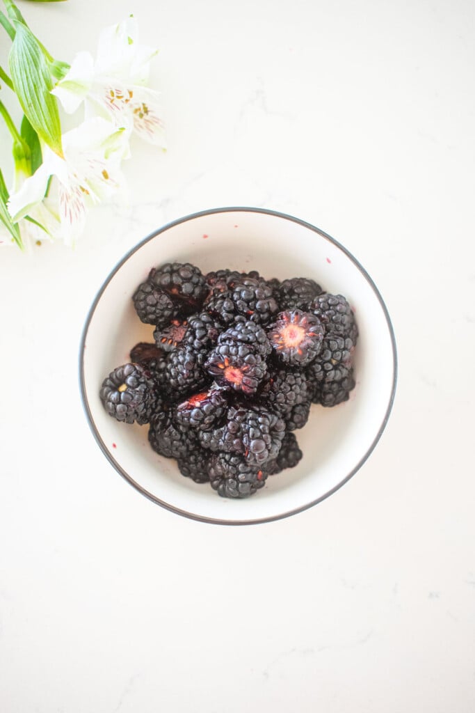 blackberries in a small bowl on a white marble counter.