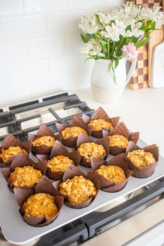 baked blackberry sweet potato muffins in a muffin pan on top of a stovetop.